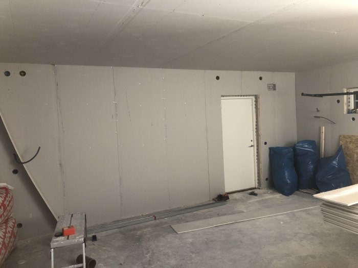 Garage under renovering med OSB och gipsade väggar och tak, elinstallationer och byggmaterial synliga.