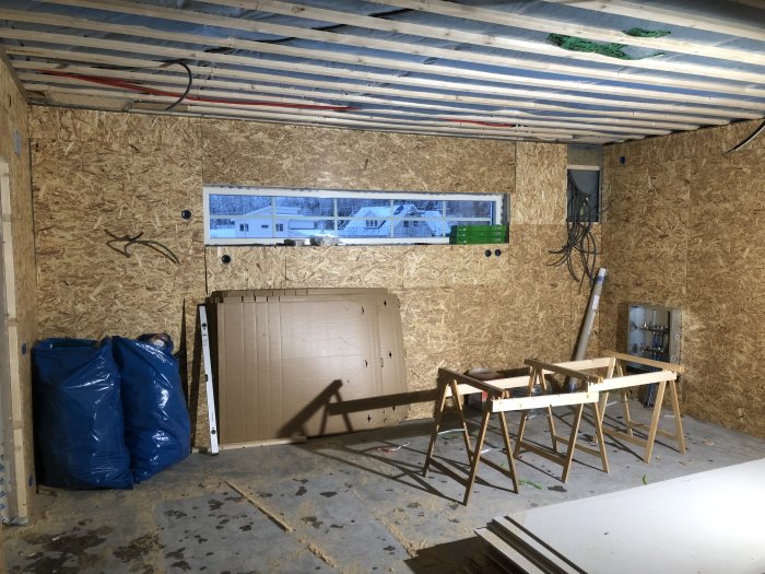 Garage under konstruktion med OSB-väggar, tak med synliga reglar och elinstallationer.