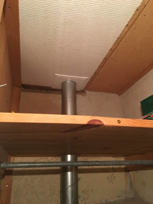 Hemmagjord ventilation med ett grått rör som går genom en vit takventil, monterat i ett träbjälklag.