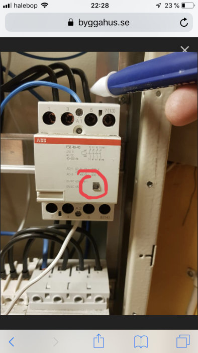 Pen pekar på en omringad knapp på ett ABB automatiskt säkerhetsbrytare.