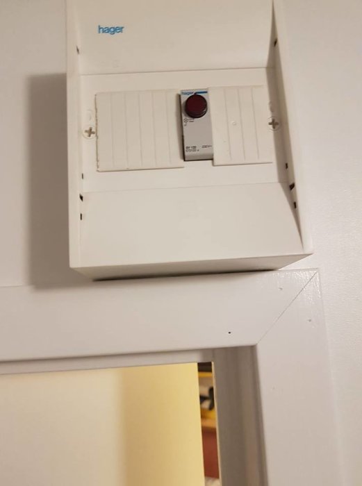 Vit Hager elektronisk termostat med röd vridknapp på en vägg, kopplad till Gnosjö element.