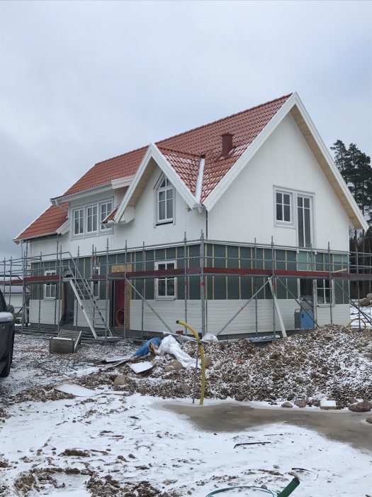 Vit lösvirkeshus under konstruktion med synliga takstolar vid en takkupa.