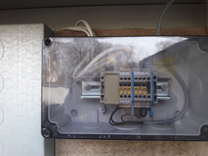 Kapsling med genomföring av flera kablar kopplade till terminalplintar, använda för elinstallation.