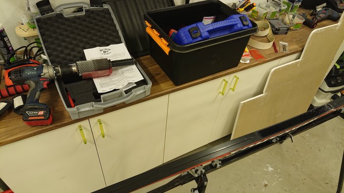 Verktygsbänk med borr, verktygslåda och byggmaterial i ett verkstadsrum. #skintech