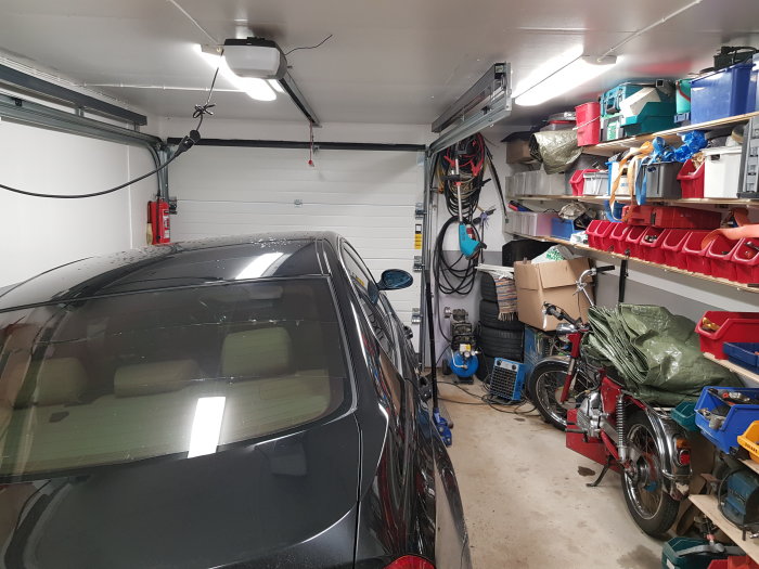 Garage med parkerad bil och moped visar ett trångt utrymme med 1 meter mellanrum och förvaringshyllor på väggen.