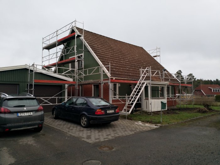 Hus och garage med nytt tak och ställningar runtom, i en bostadsmiljö.