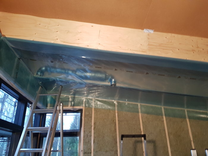 Isolering och plastfolie monterat mellan takbjälkar i ett renoveringsprojekt, med synliga ventilationsrör.