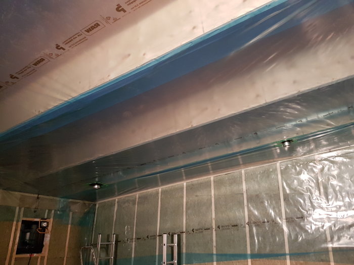 Isolering och plast installerade mellan takbalkar med synlig ventilation och rörgenomföringar.