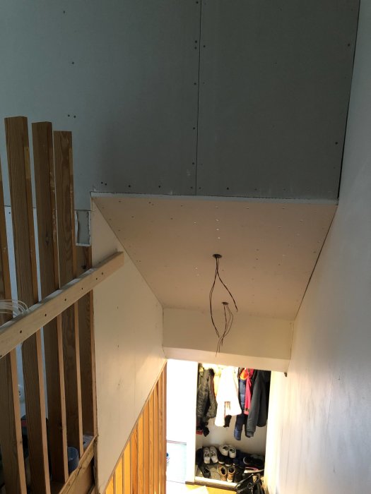 Nyinstallerade gipsskivor på vägg och tak över trappa i ett hem under renovering.