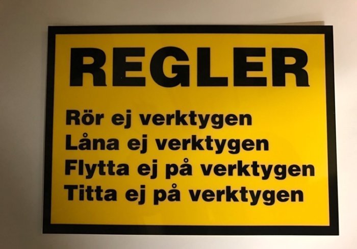 Gul och svart skylt med texten "REGLER" och humoristiska förbud gällande verktyg.