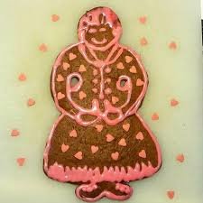 Pepparkaksgubbe dekorerad med rosa glasyr och hjärtan på grön bakgrund.