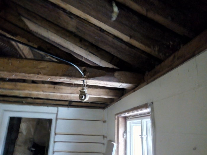 Utsatt takstol och bjälklag med synliga spikar efter borttaget innertak i ett renoveringsprojekt.