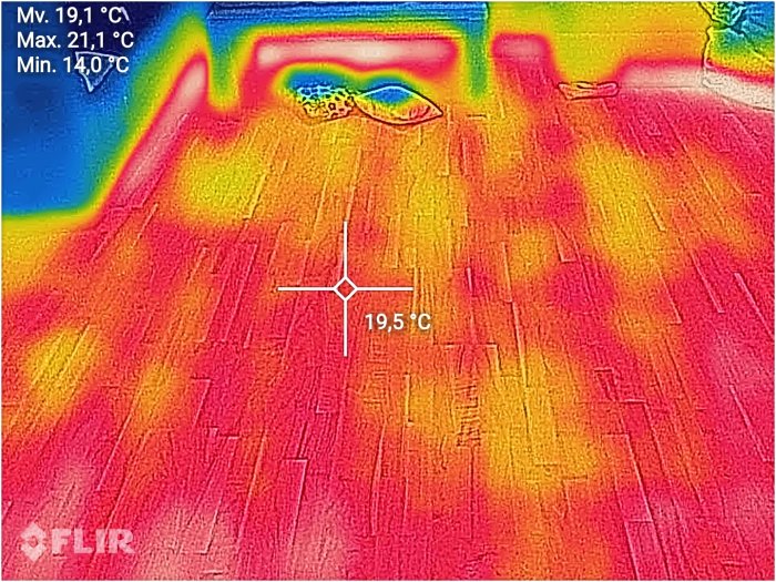 Värmekamerabild av golvet med temperaturöverlägg, visar ojämn värmefördelning i ett hus.