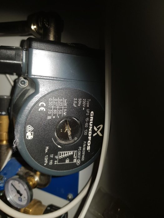 Cirkulationspump märkt Grundfos installerad i ett värmefördelarskåp.