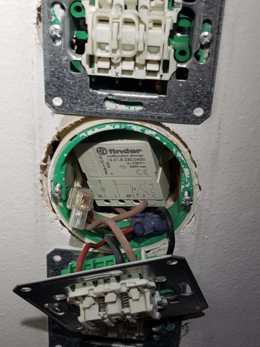 Öppen elinstallation med tre exponerade dimmers och synlig märkning på en av enheterna, kopplingskablar och fästelement.