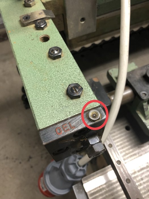 Smörjnippel på en äldre maskin med texten "OEL" på metallen, indikerar oljepåfyllning.