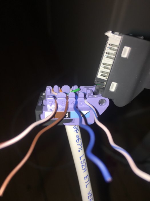Nätverkskabel kopplad till en kontaktdon med synlig märkning för kopplingsschema A och B.