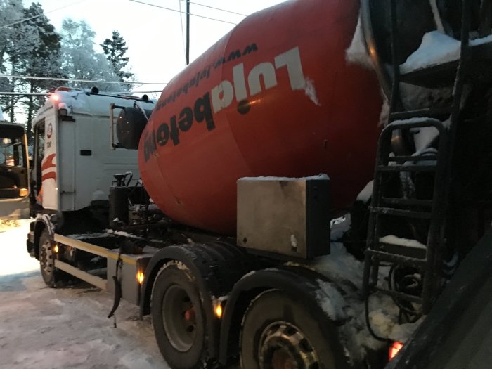 Bild på en betongbil i vintermiljö under byggprojekt med synliga hydraulslangar och snö.