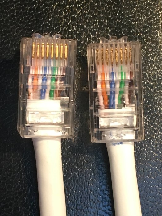 Två RJ45-nätverkskontakter med synliga färgkodade kablar innan krimpas.