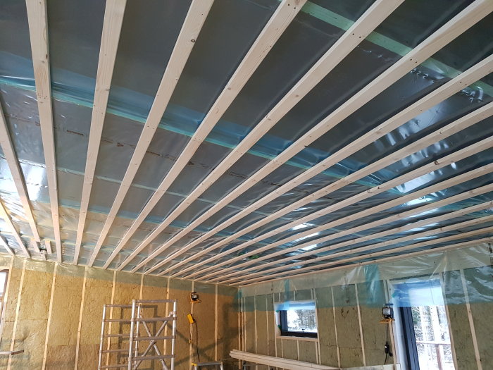 Tak med glespanel och isolering i ett pågående byggprojekt, med en begagnad rullställning synlig.