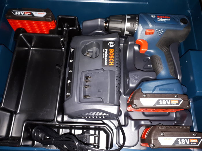 Bosch borrskruvdragare med batterier och laddare i en blå plastväska.