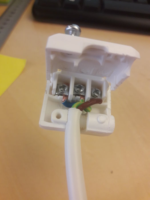 Eluttag med ansluten lampsladd och öppen kopplingsplint, indikerar begränsat utrymme.