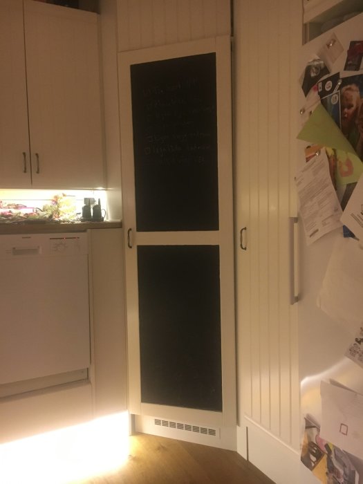 Norcool hörnkylskåp integrerat i vit köksinredning med anslagstavla och anteckningar.