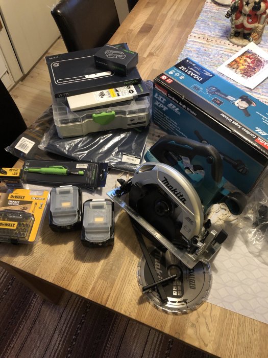 Nya verktyg och tillbehör på ett bord, inklusive en Makita cirkelsåg, batterier och DeWalt bits.