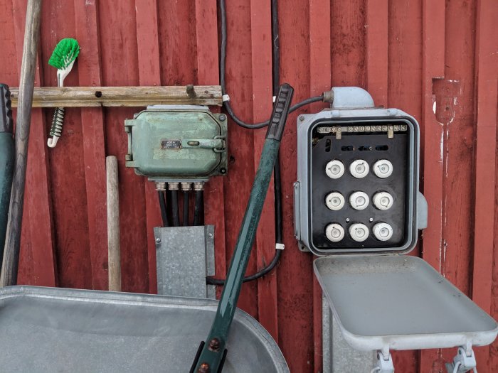 Öppet proppskåp på röd vägg med säkringar, översta vänstra proppen utlöser ofta, intill en gammal elklocka.