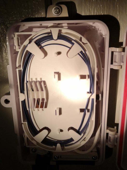 Öppen fasadbox med organiserade blå fiberkablar redo för sista svetsningssteget.