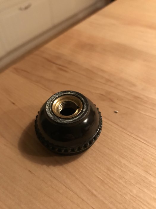 Gängad lamphållartopp på ett träunderlag.
