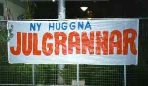 Banner med texten "NY HUGGNA JULGRANNAR" hängande på staket.