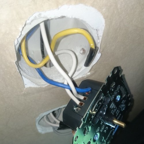Öppet eluttag med löstaget dimmer-switch och synliga kablar, gul kabel oanvänd.