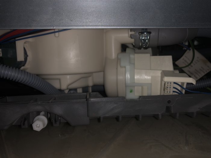 Installation av plastavlopp under diskbänk med anslutna vattenrör och elektriska ledningar.