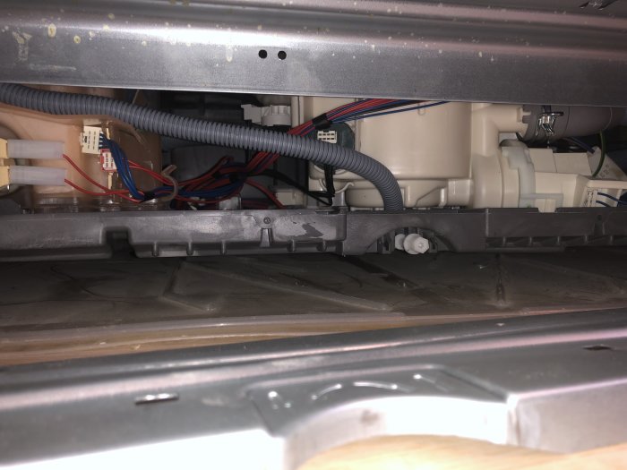 Underrede av diskmaskin som visar slangar, kablage och mekaniska komponenter.