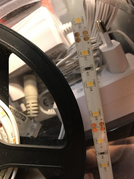 LED-list med klippmärken och dioder på bord i rörigt rum.