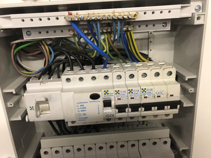 Elektriskt skåp med öppet säkringsblock, ledningar och jordfelsbrytare, fråga om korrekt installation.