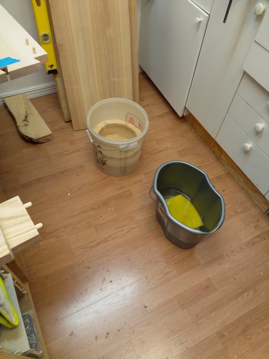 Verkstadsrum med skåpdelar, hink med lim och verktyg under byggprocessen.