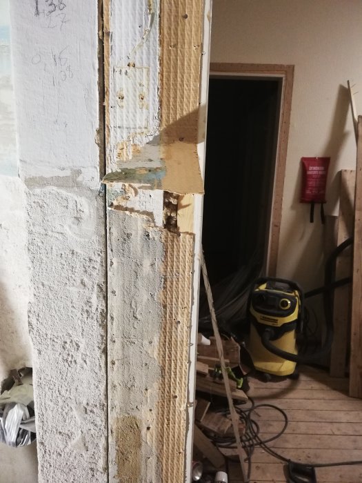 Ojämnt betongblock bredvid en dörrkarm med synlig nivåskillnad, verktyg och byggmaterial i bakgrunden.