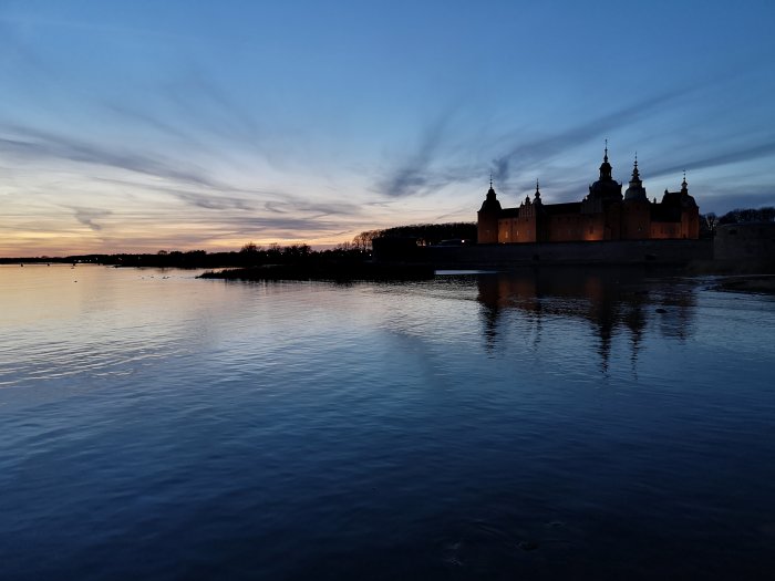 Solnedgång över Kalmar sund med silhuetten av Kalmar slott mot kvällshimmeln.