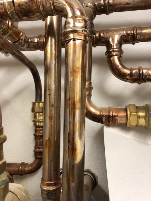 Kopparrör med missfärgningar och fläckar i pannrum, eventuell korrosion eller kemisk reaktion.