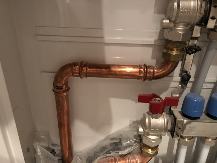 Kopparrör med lätt missfärgning och anslutningar i ett pannrum.