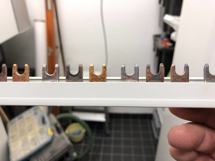 Närbild på en lös fasskena med missfärgade och delvis rostiga kopparanslutningar.