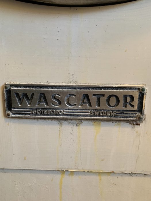 Sliten metallskylt på maskin med texten "WASCATOR GÖTEBORG SWEDEN" och synliga korrosionsspår.
