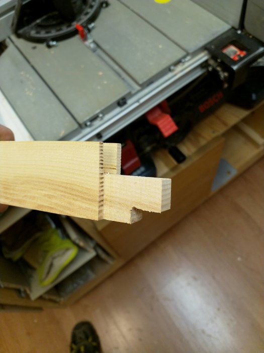 Träbit med haunched tenon-förband framför bordsåg i verkstad.
