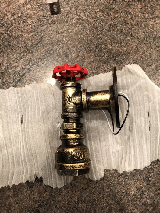 Lampa med fel form och färg, rödrostigt utseende, ligger på en vit duk mot granitbänk.