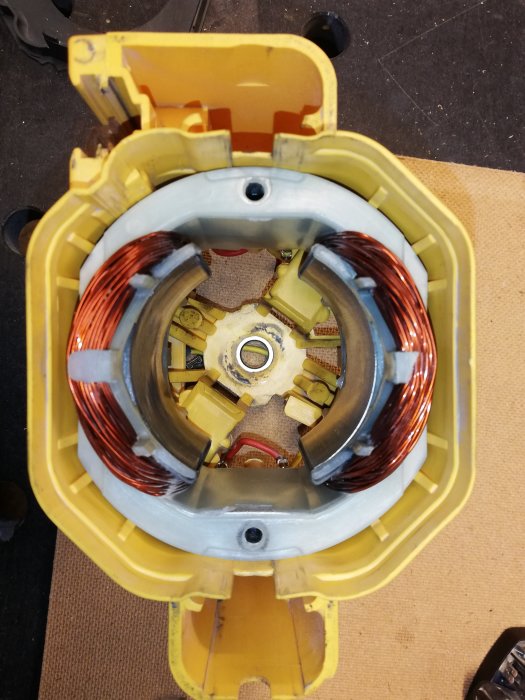 Öppen elektrisk motor med synlig rotor och stator som visar tecken på skador efter att ha tappats på golvet.