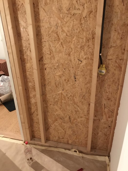 Rivning av vägg med träreglar och OSB-skivor, mätinstrument hänger på en regel, golvet skyddat.