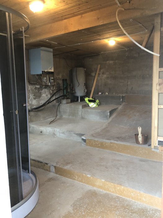 Interiör av ett garage med exponerade betongväggar, några med puts och flagnande färg, och en betongtrappa.