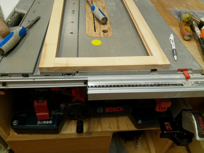 Träskenor och ramdelar på en bordsåg i en verkstad, redo för precisionssågning och montering.
